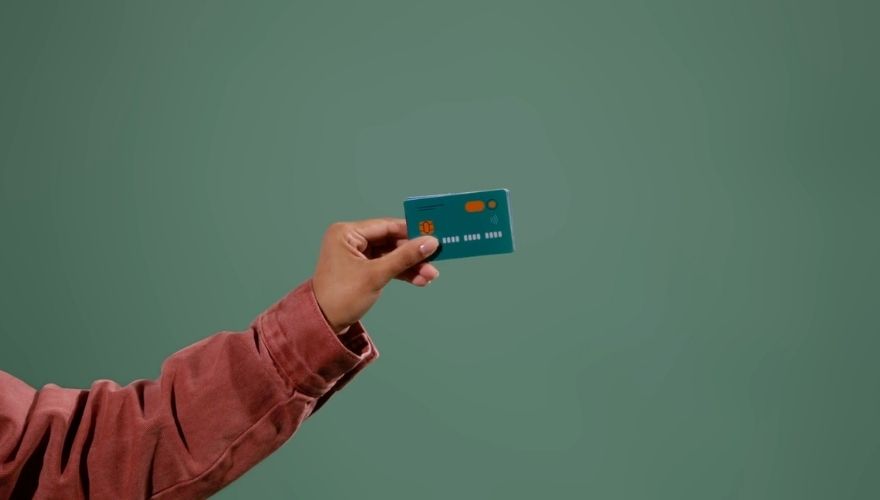 Person holding a credit card against a plain green background.